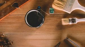 a cup of tea on a wooden worktop with paint brushes on the side
